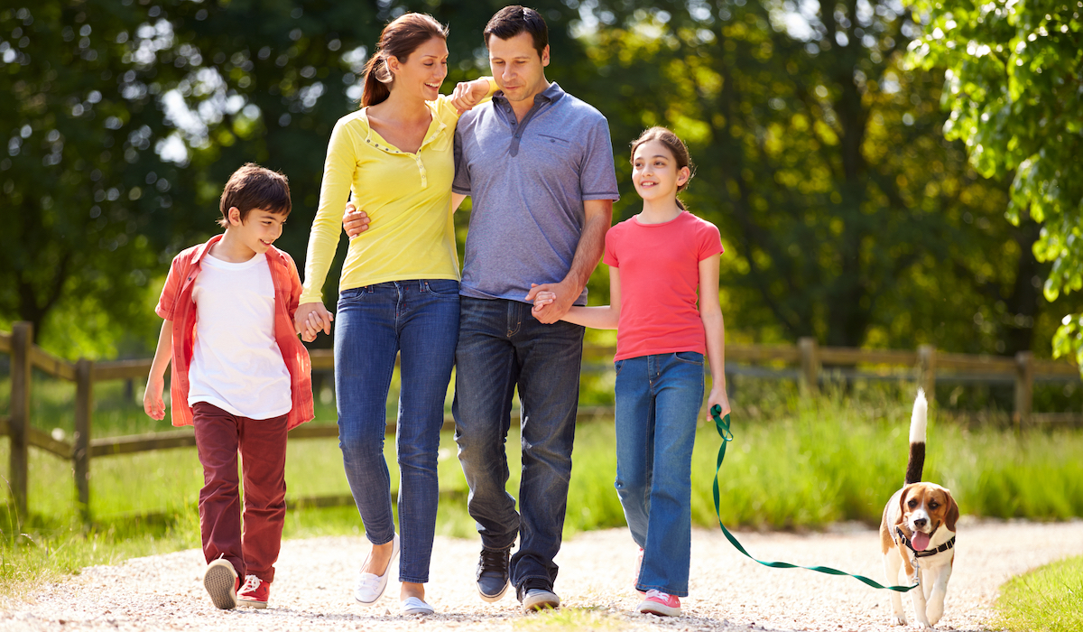 Hispanic Family Taking Dog For Walk In Countryside